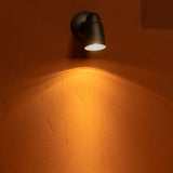Ealing Außenwandstrahler – Bronze – Licht, das von einer Terrakotta-Steinwand nach unten strahlt. 